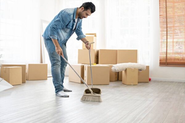 A man sweeping the floor in a home with moving boxes, representing Move-In & Move-Out Cleaning Services in Fuquay Varina, NC.