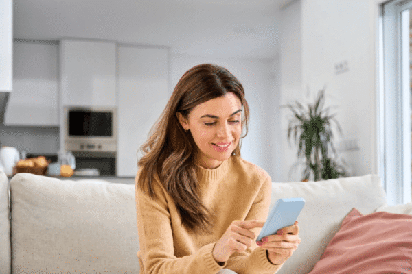 A woman on a couch, engaged with her phone, appearing relaxed and comfortable